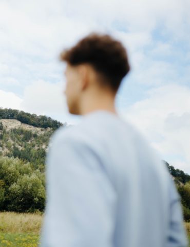 A man standing in a field looking at a hill