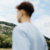 A man standing in a field looking at a hill