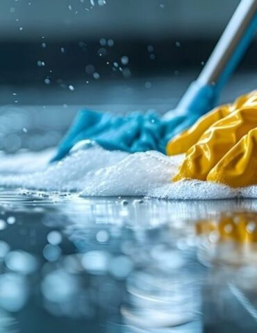 A person in yellow gloves and blue gloves cleaning a floor