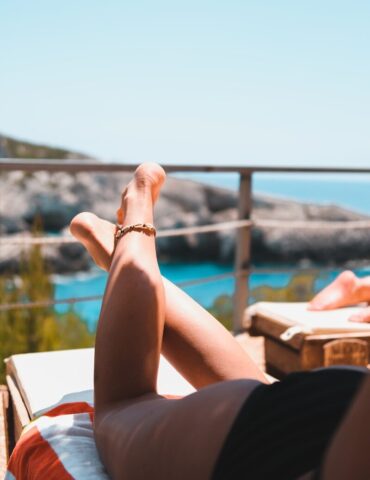 person wearing gold bracelet and bracelet sitting on brown wooden bench during daytime