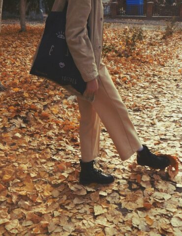 A woman walking through a leaf covered park